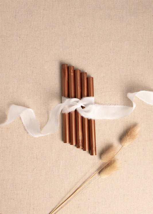 Chocolate brown wax seal sticks tied with white silk ribbon and surrounded by dried flowers