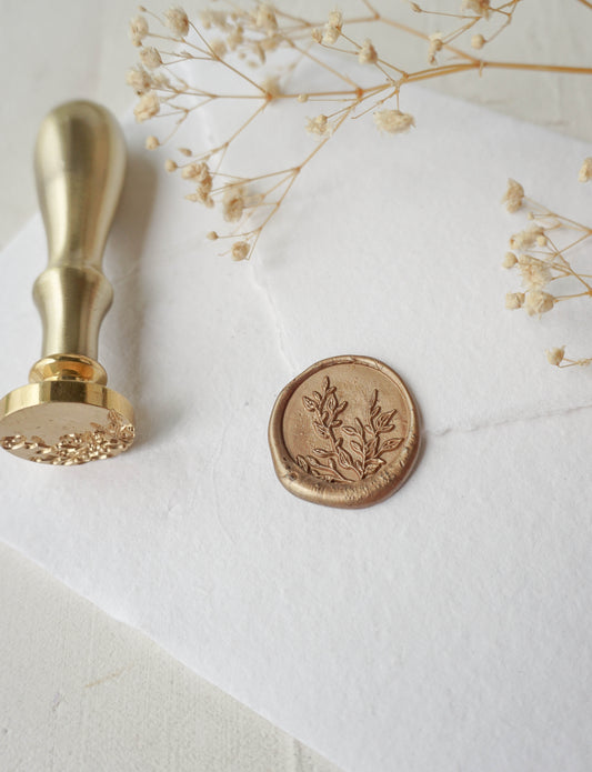 Leaf wax stamper on white handmade paper surrounded by dried flowers