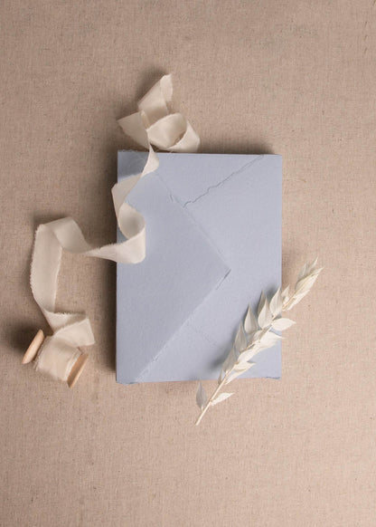  5x7 inch Light Blue Handmade paper sheet with deckle edge surrounded by dried flowers and cream silk ribbon spool