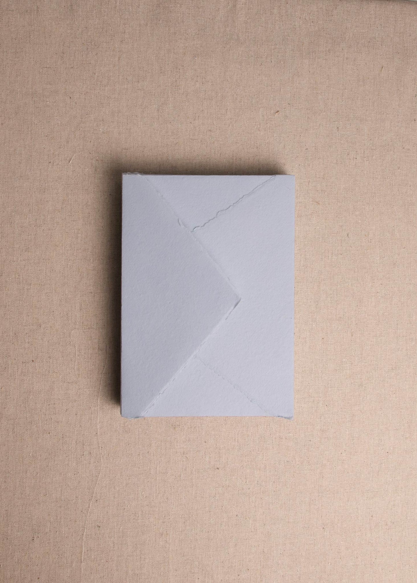 Singular 5x7 Light Blue Handmade paper envelope with deckle edge on linen background