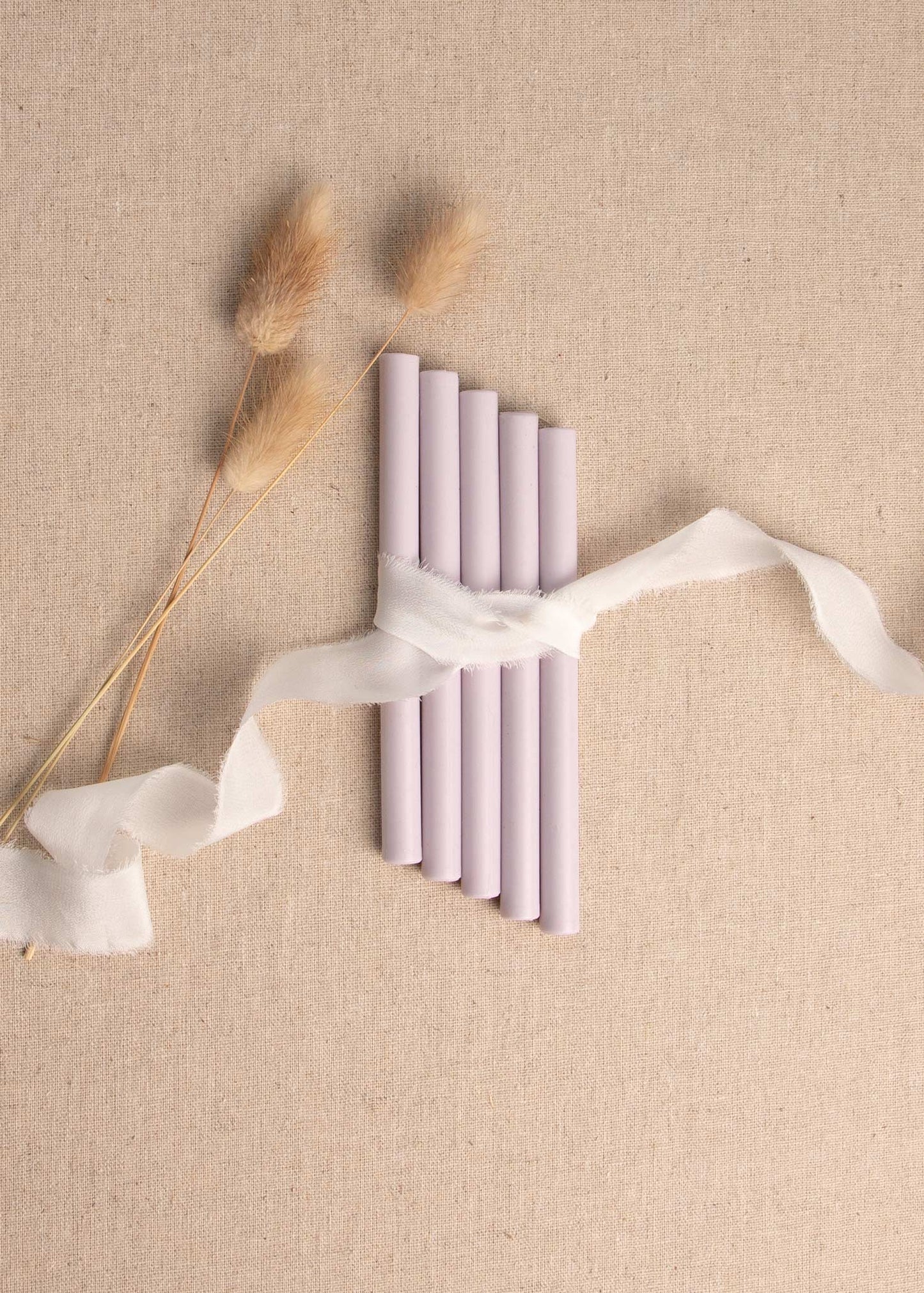 5 pack of Lilac Linen wax seal sticks surrounded by white silk ribbon and dried flowers