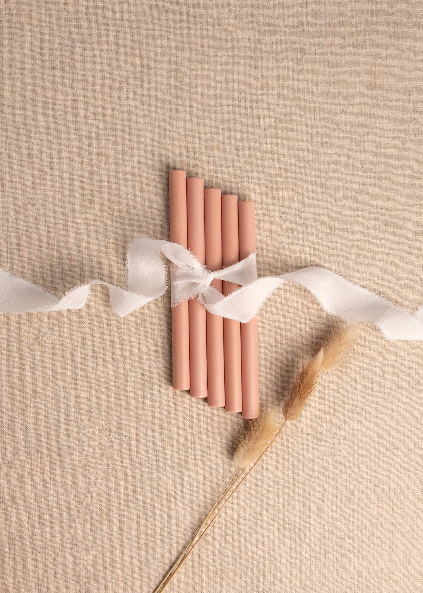 Peach Pink wax seal sticks tied together with white ribbon and dried flowers 