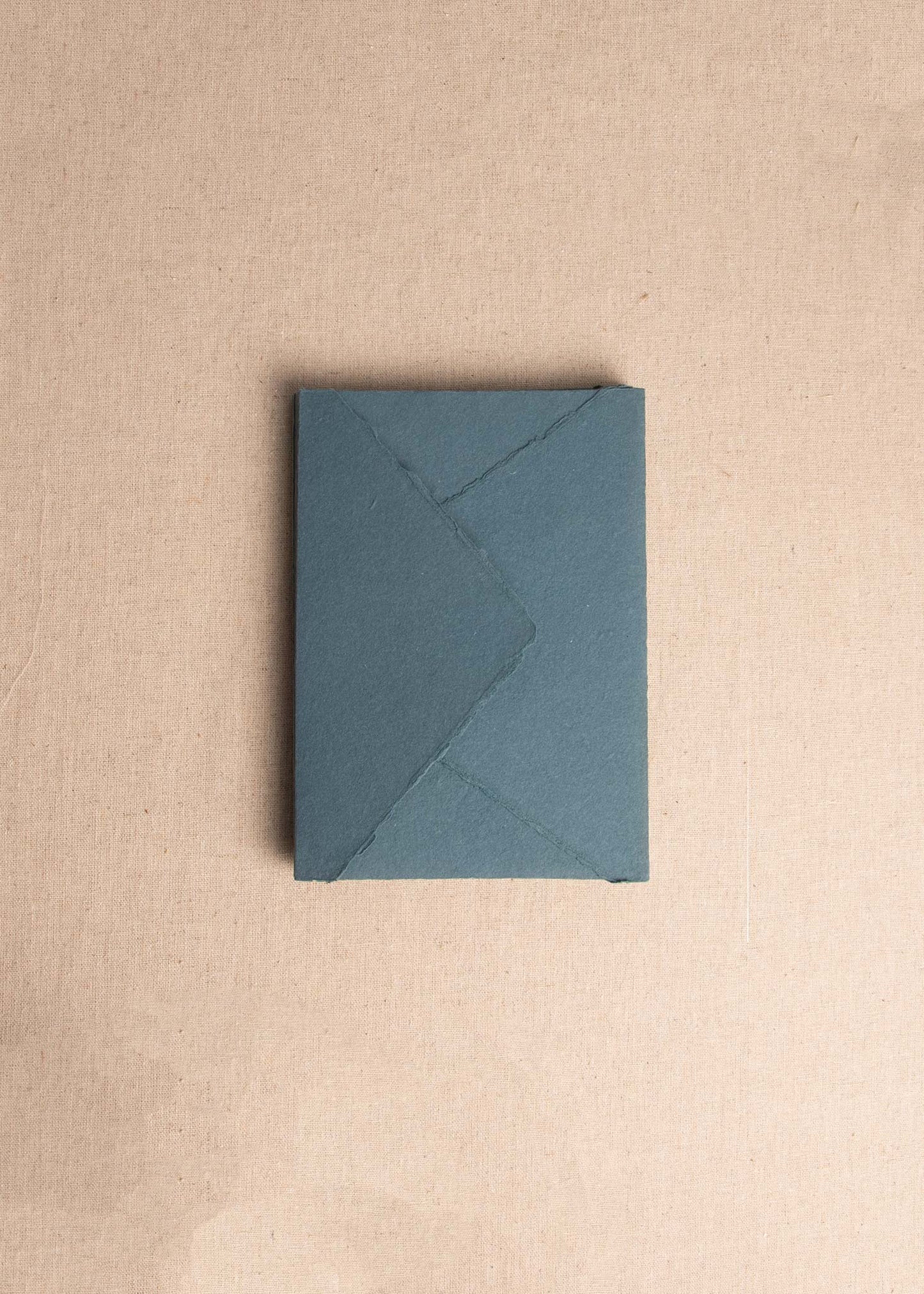 Singular 5x7 inch Teal Handmade paper envelope with deckle edge on linen background