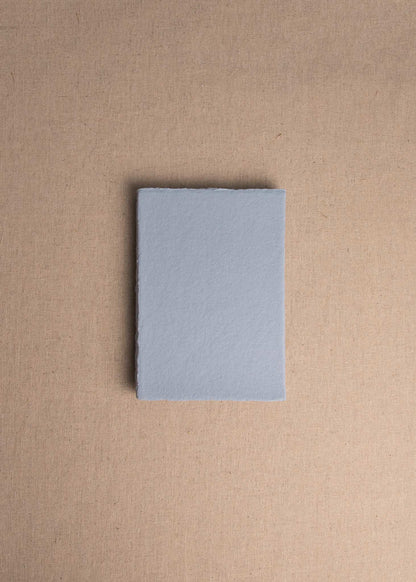Singular 5x7 Dusky Blue Handmade paper envelope with deckle edge on linen background