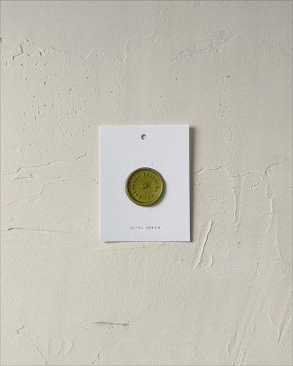 Elevated view of Olive Green wax seal stamp sample on textured background