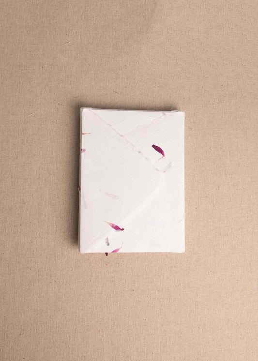 Pile of floral dried petal handmade paper envelopes with deckle edge on linen background