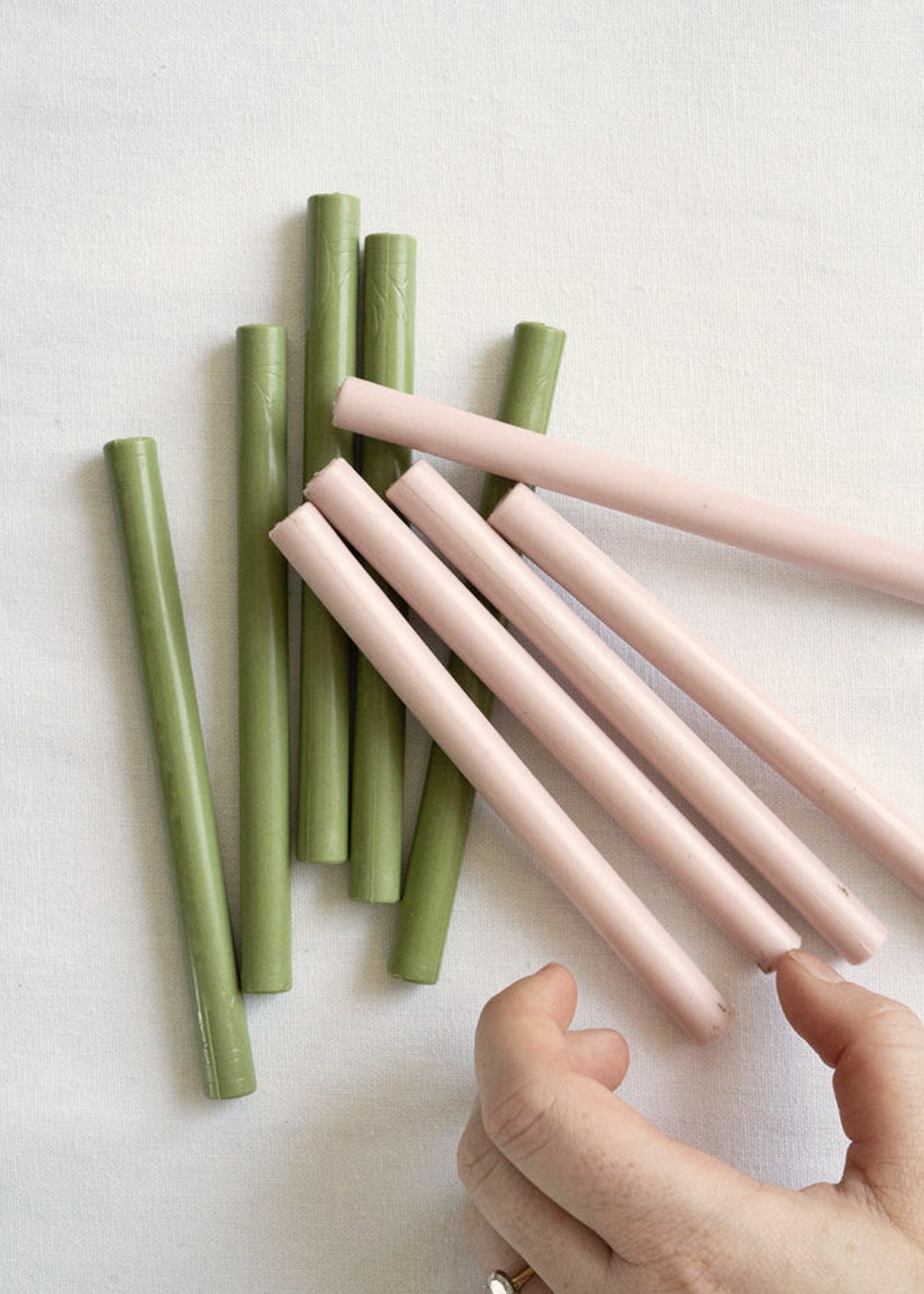 Green and pink wax seal sticks with woman's hand