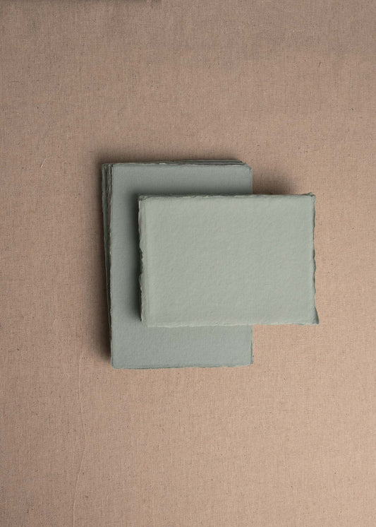 Pile of Jade Green handmade paper with deckle edge on linen background