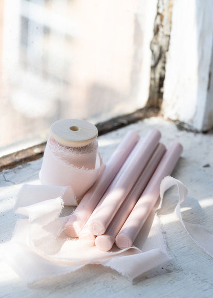 Soft pink wax seal sticks with silk ribbon by antique window 