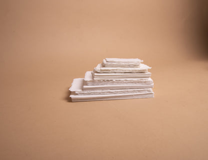 Stack of vertical various sizes of white handmade paper with deckle edge