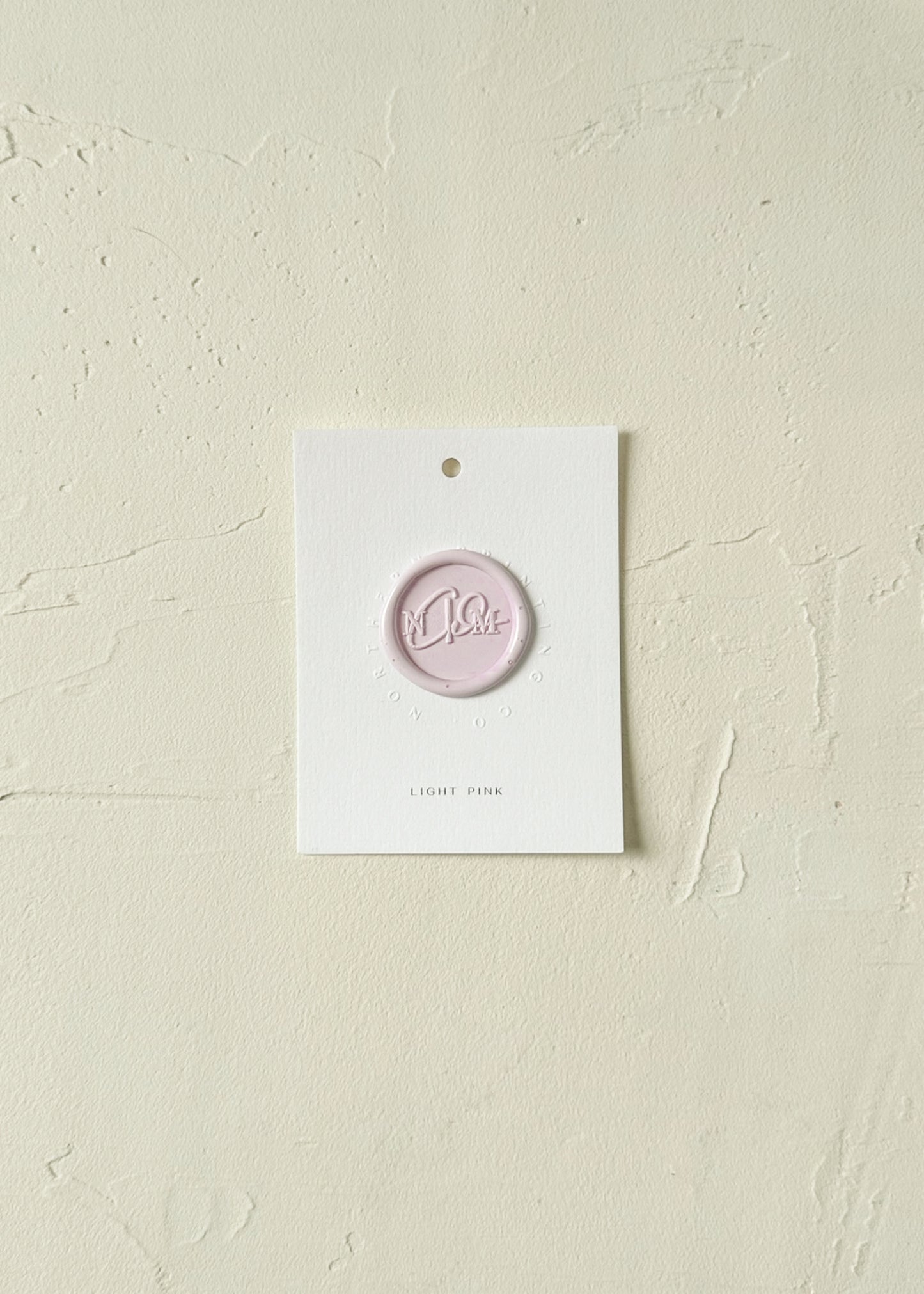 Elevated view of Light Pink wax seal stamp sample on textured background