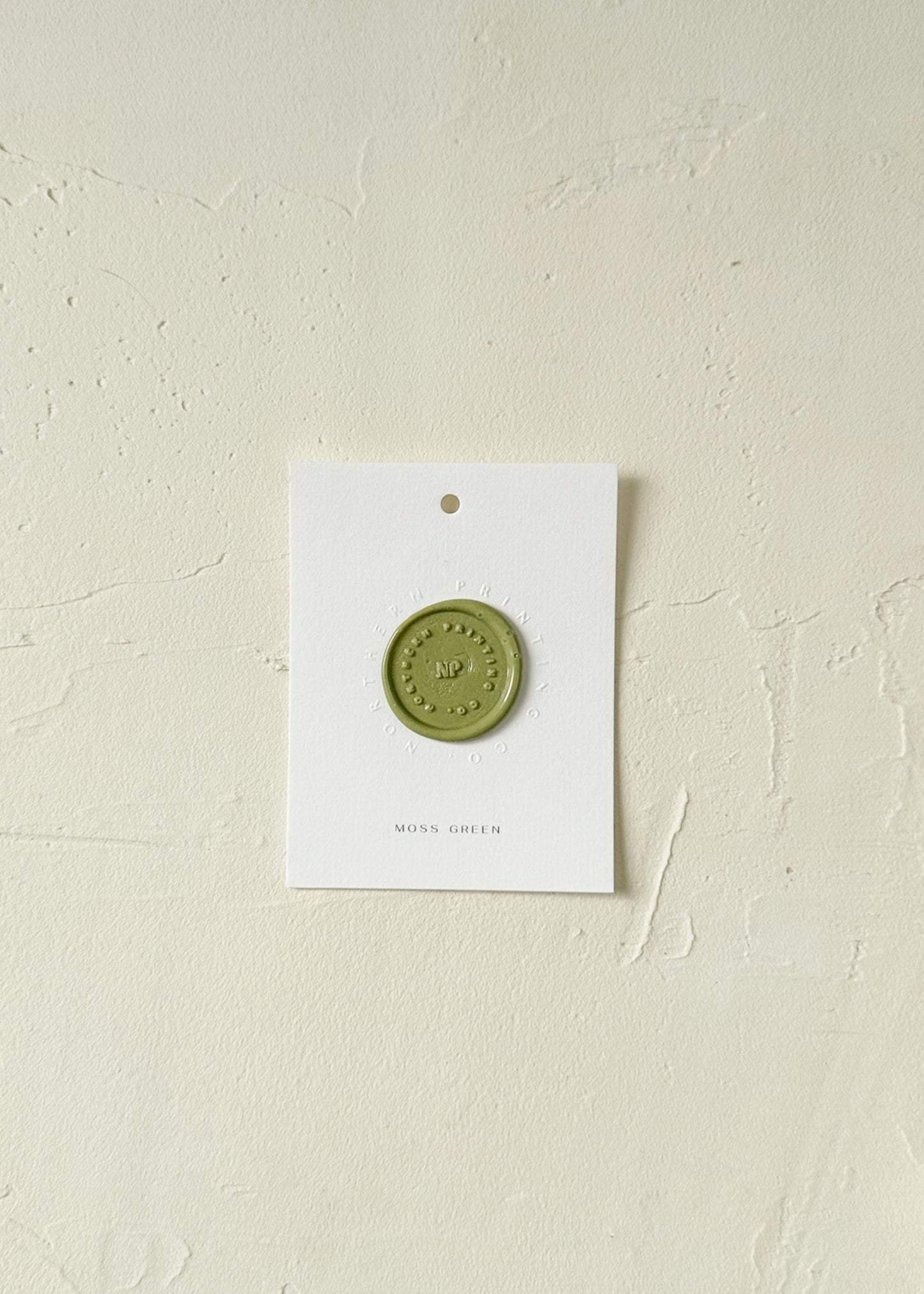 Elevated view of Moss Green wax seal stamp sample on textured background