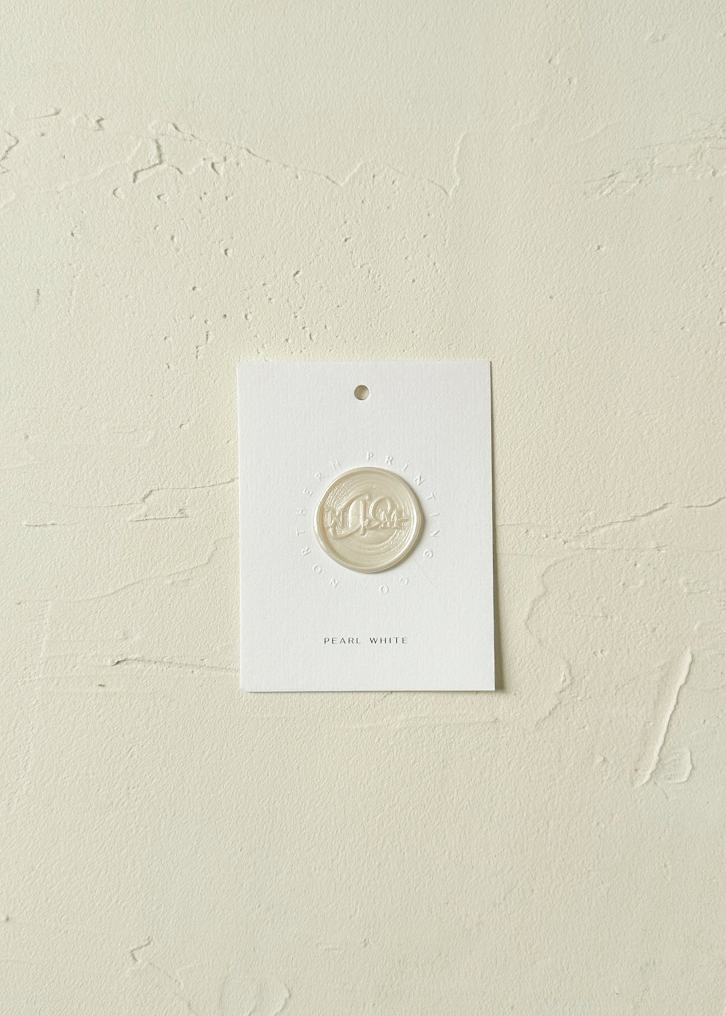 Elevated view of Pearl White wax seal stamp sample on textured background