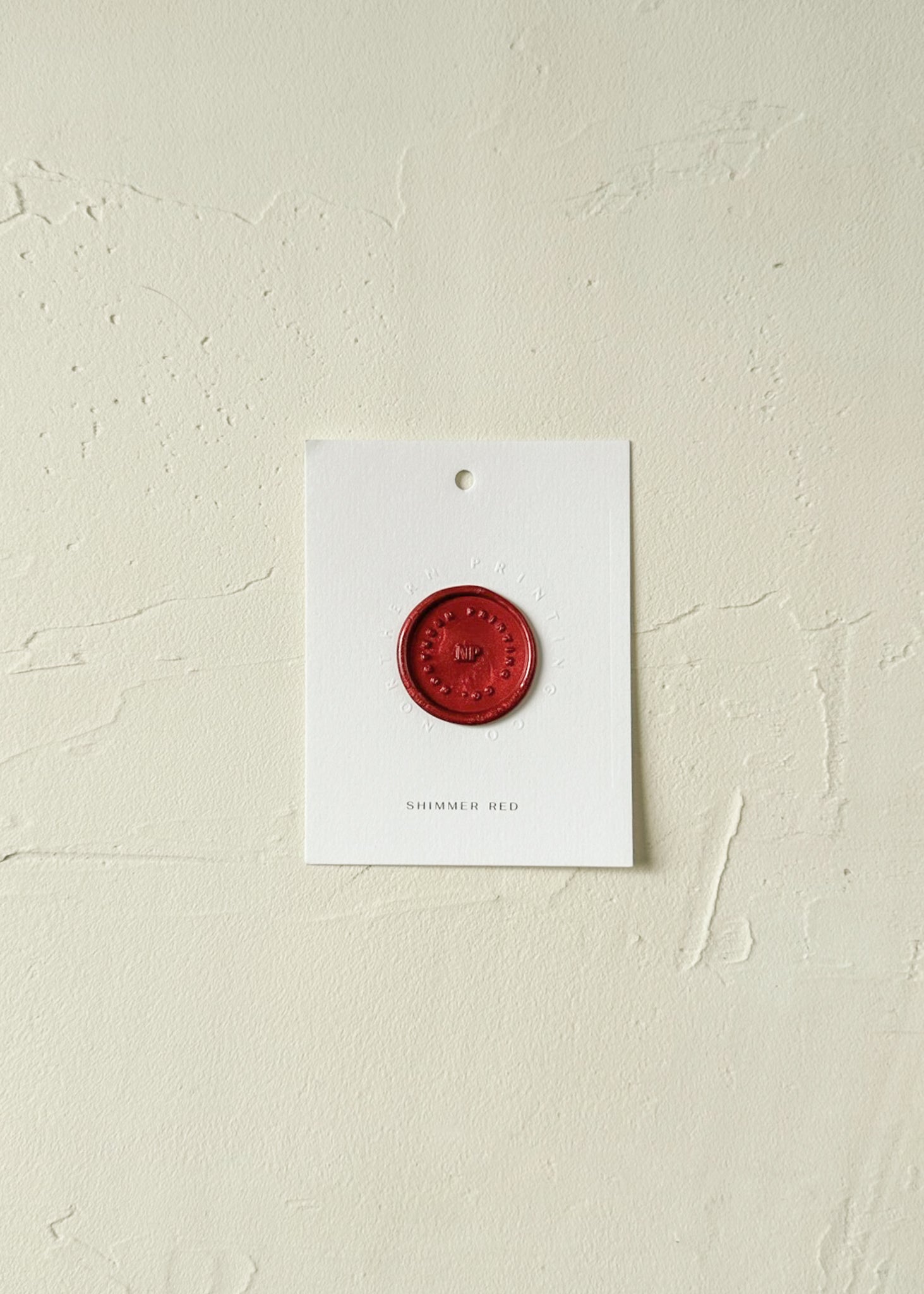 Elevated view of Shimmer Red wax seal stamp sample on textured background