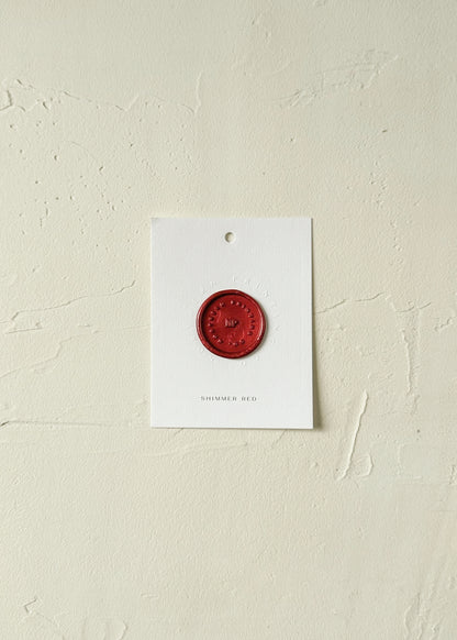 Elevated view of Shimmer Red wax seal stamp sample on textured background