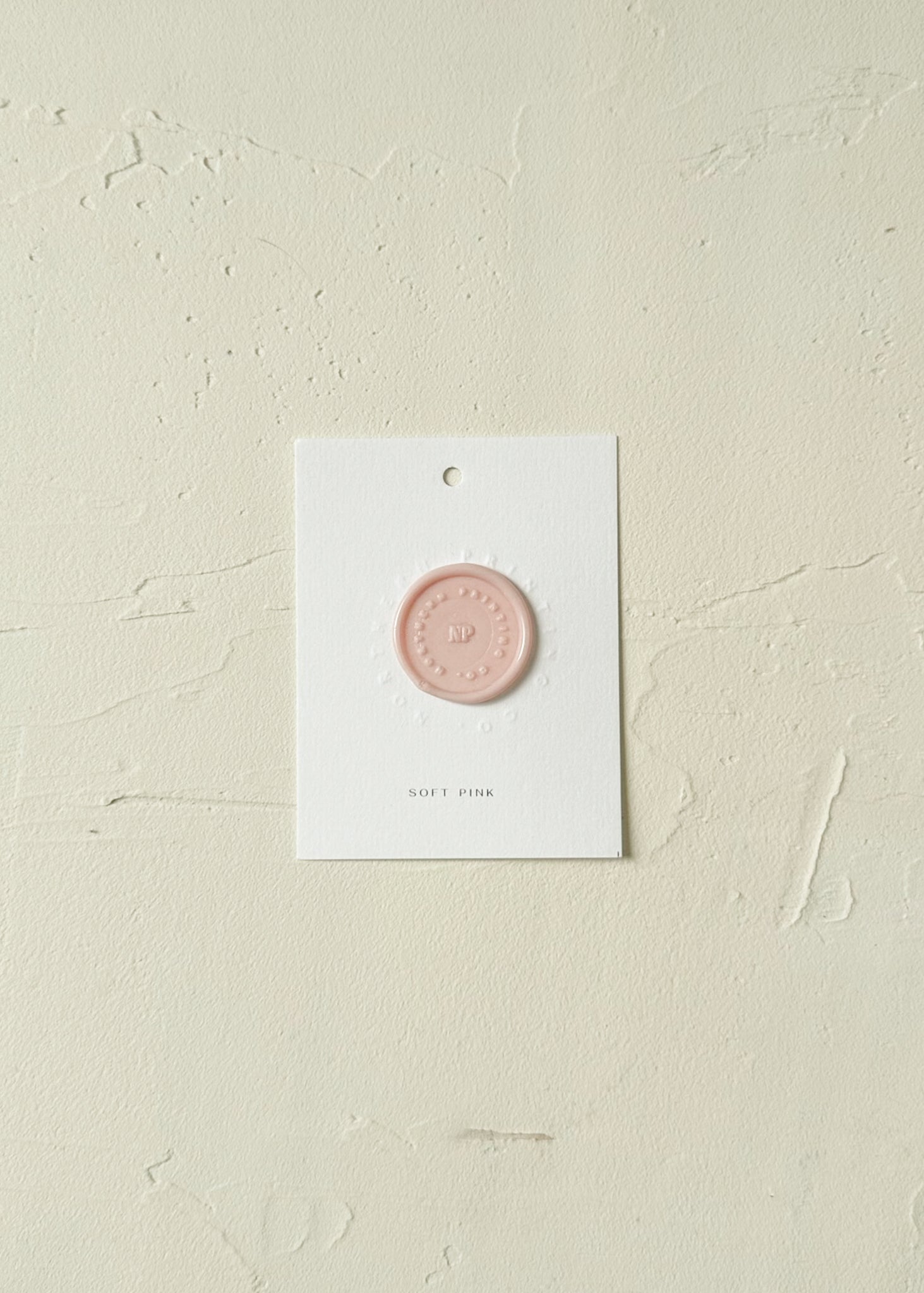Elevated view of Soft Pink wax seal stamp sample on textured background
