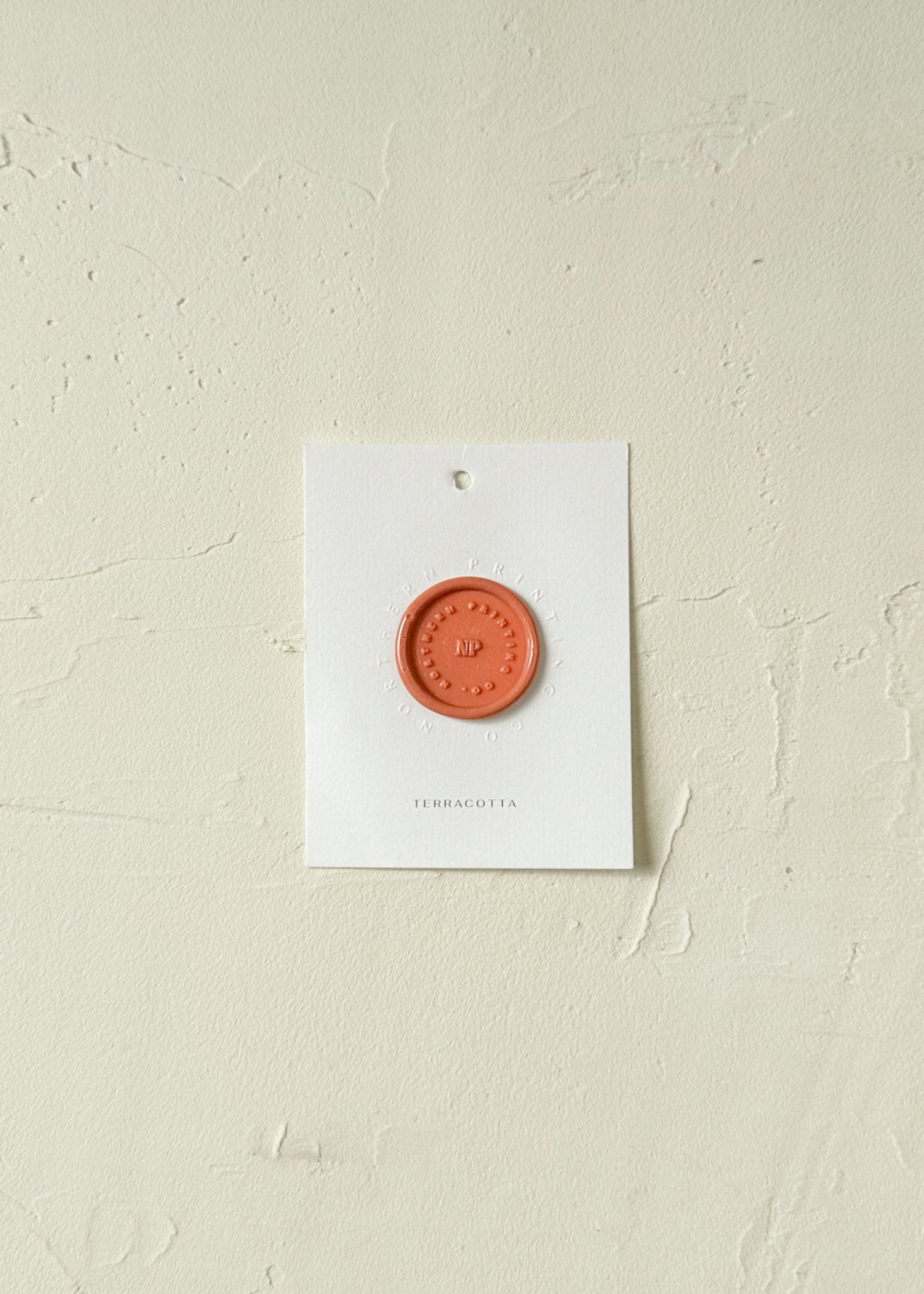 Elevated view of terracotta wax seal stamp sample on textured background