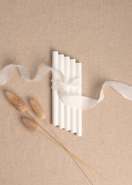 White wax seal sticks on linen background with white silk ribbon and dried flowers