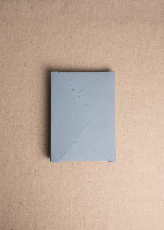 Singular 5x7 Dusky Blue Handmade paper envelope with deckle edge on linen background